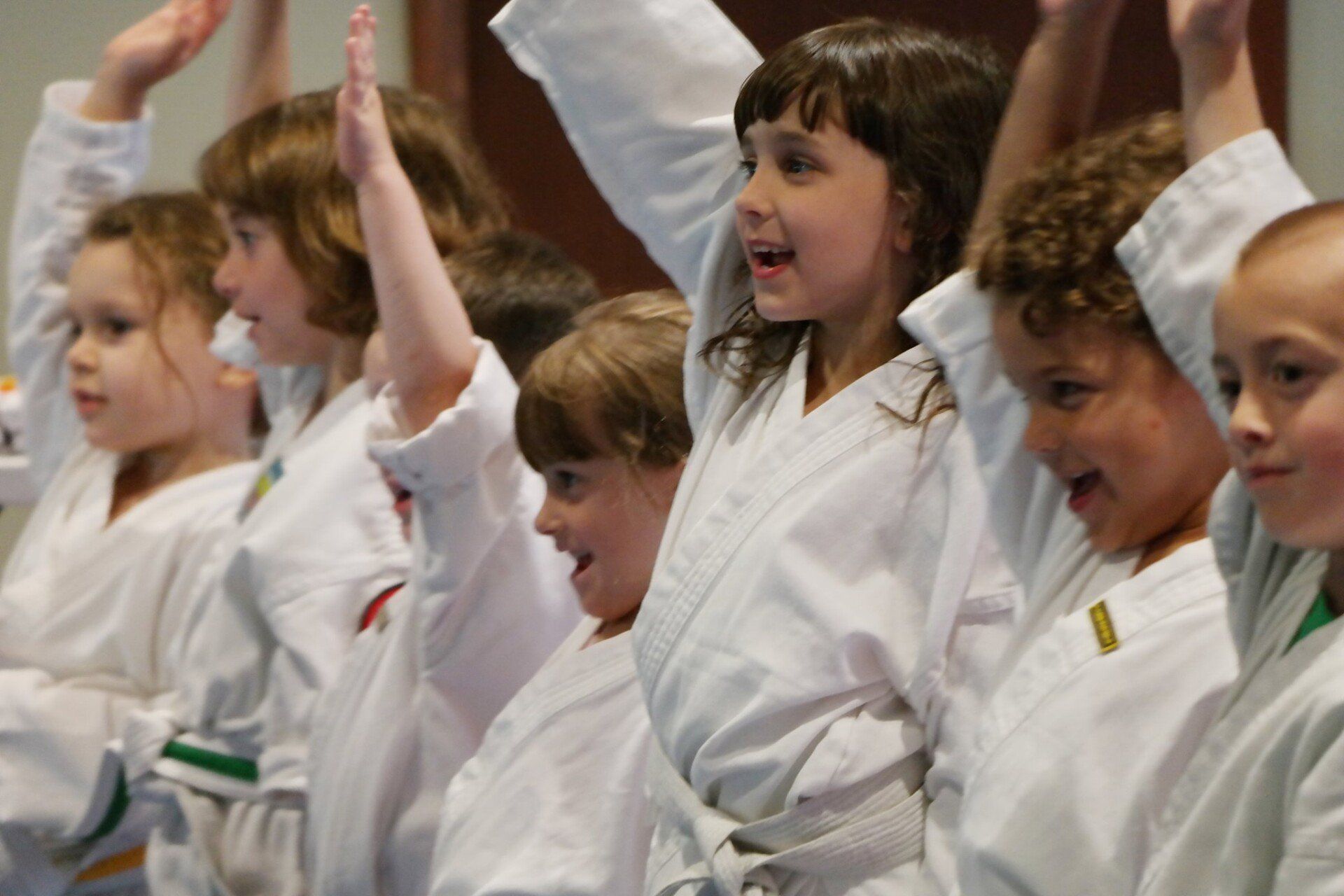 A group of young children are raising their arms in the air.