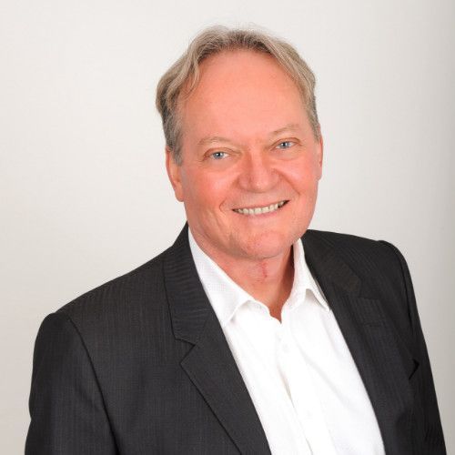 A man in a suit and white shirt is smiling for the camera.