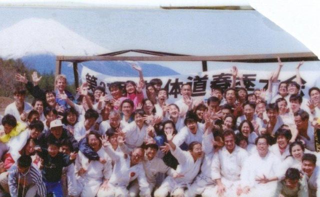 A large group of people are posing for a picture in front of a sign with Chinese writing on it