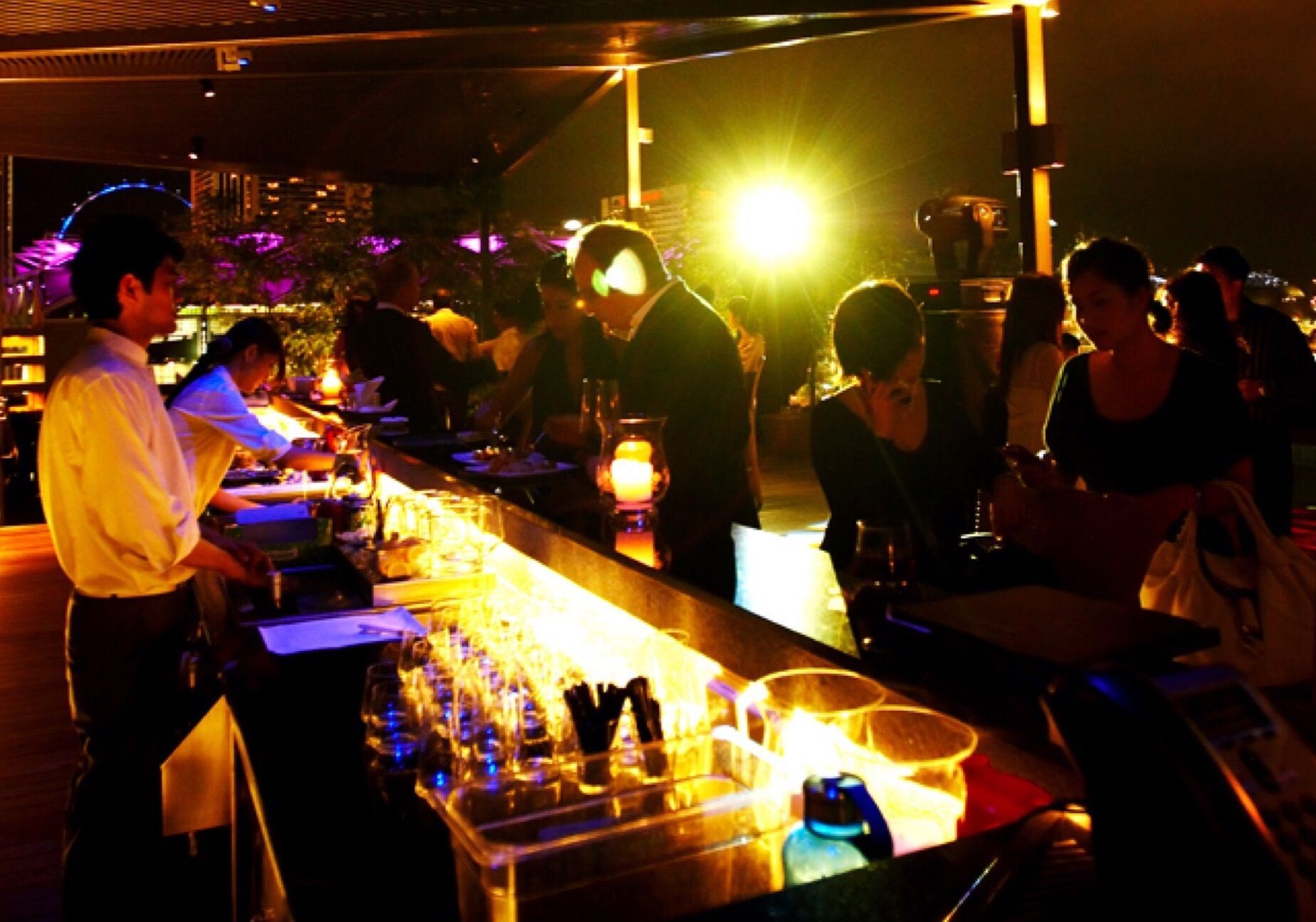 A group of people are sitting at a bar at night
