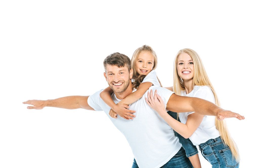 A man and woman are giving a little girl a piggyback ride.
