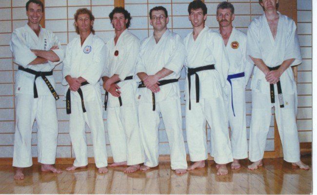 A group of men in karate uniforms are posing for a picture