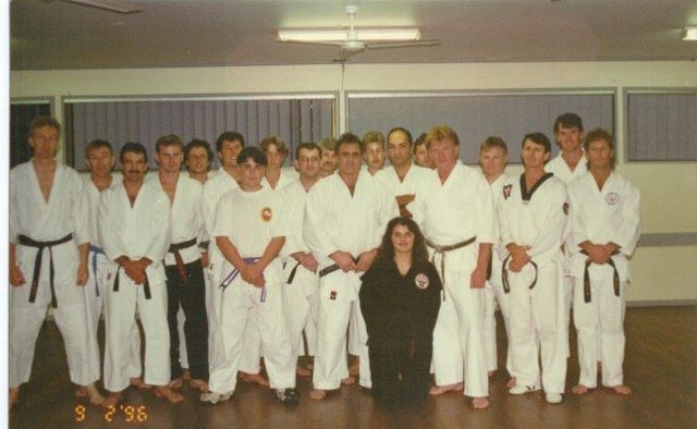 A group of people in white karate uniforms pose for a photo