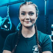 A woman with braids is smiling for the camera in a gym.