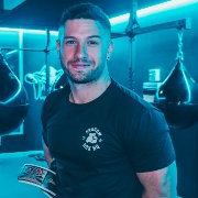 A man in a black t-shirt is holding a magazine in a gym.