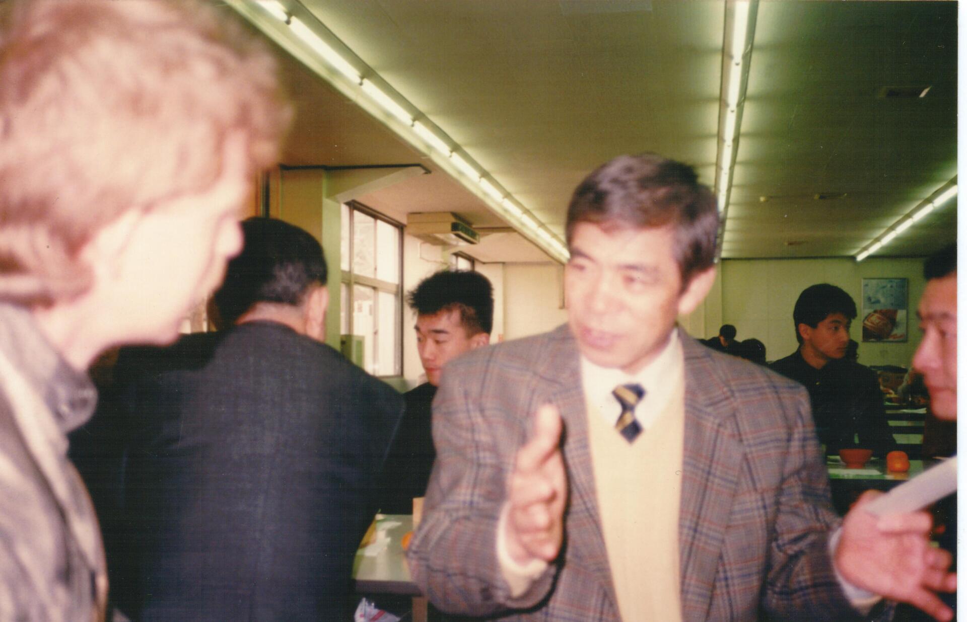 A man in a suit and tie is talking to a woman in a restaurant.