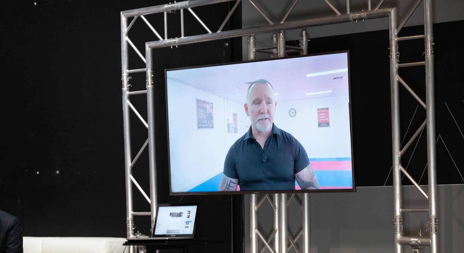 A man with a beard is talking on a television screen.