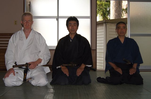 Three men are sitting on the floor holding swords