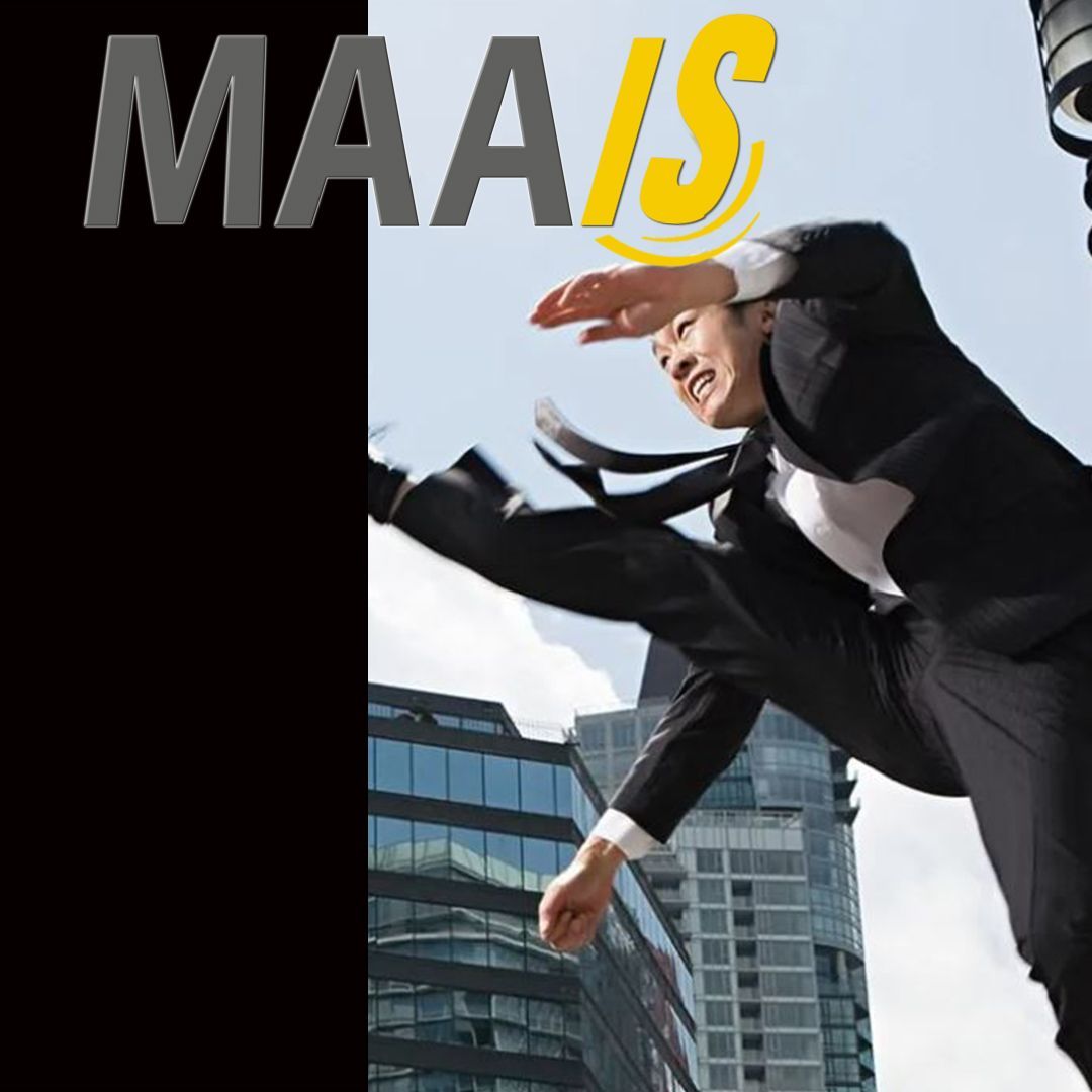A man in a suit is jumping in the air with the word maais behind him