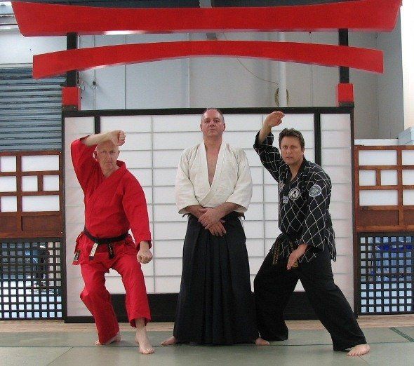Three men in martial arts uniforms pose for a picture