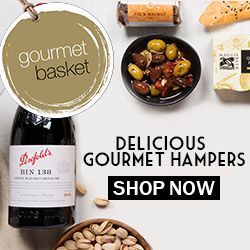 A gourmet basket with a bottle of wine , bowls of food , and nuts.