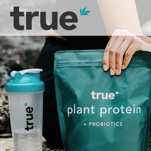 A person is holding a bag of true plant protein next to a shaker.