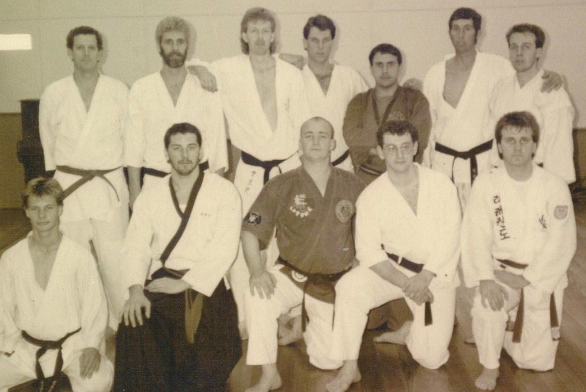 A group of men in karate uniforms pose for a photo