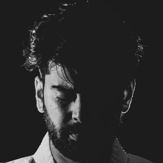 A man with a beard is looking down in a black and white photo.