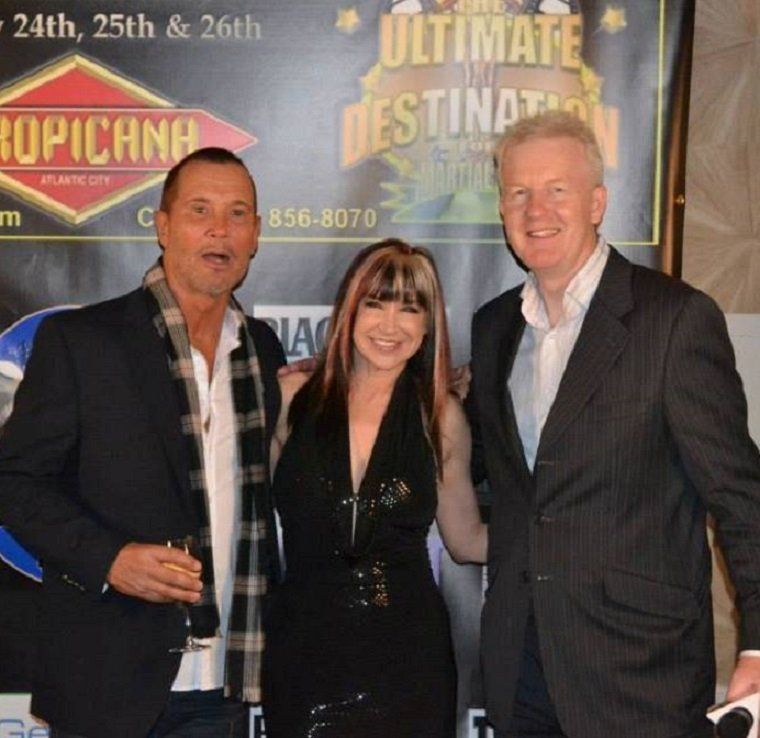 Three people posing in front of a sign that says the ultimate destination