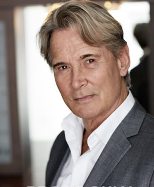 A man in a suit and white shirt is looking at the camera