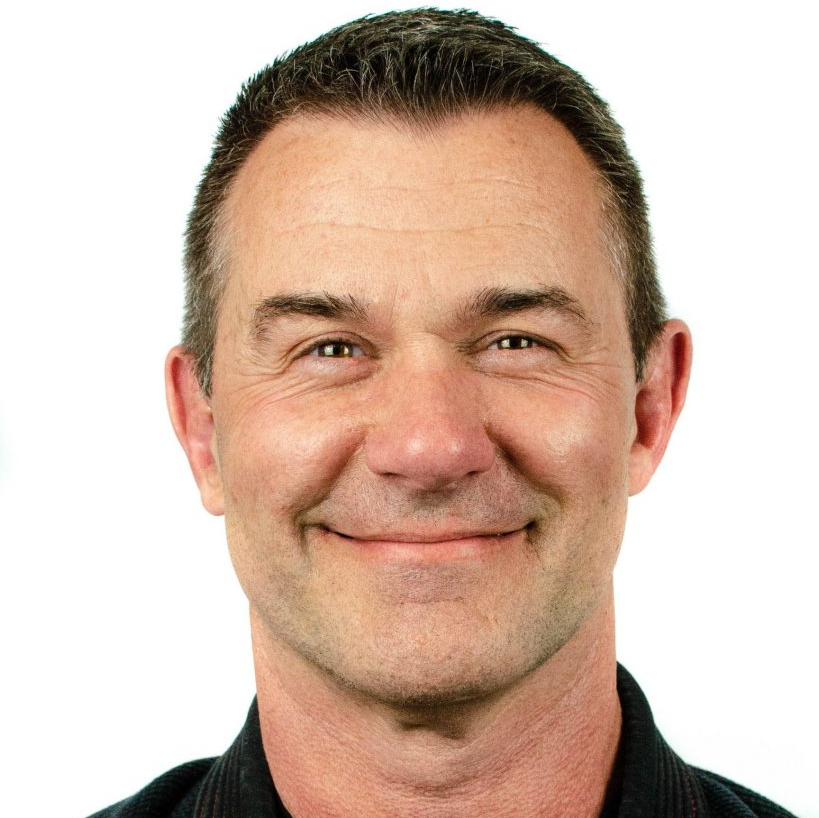 A man wearing a black shirt is smiling for the camera