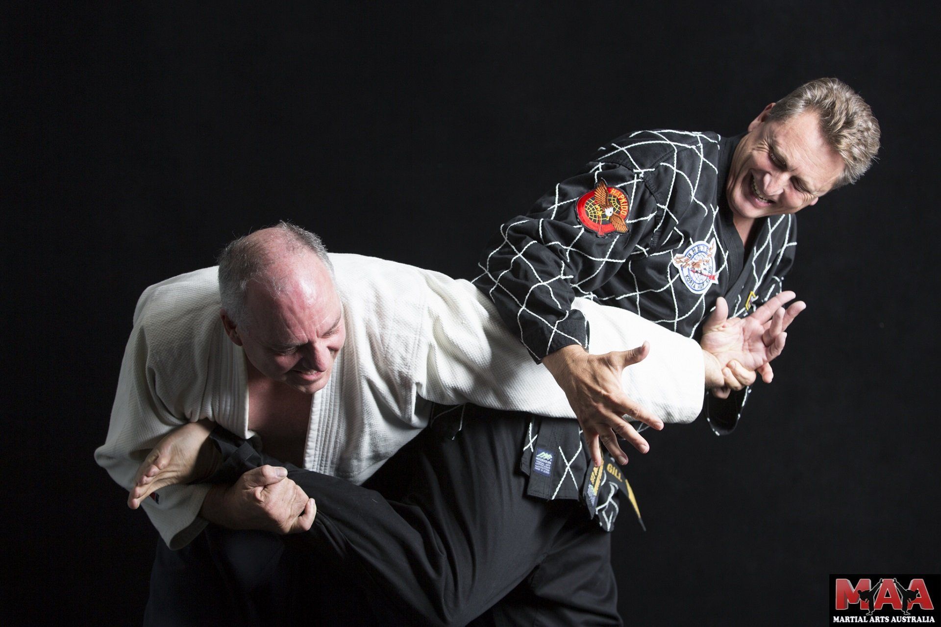 Two men are practicing martial arts with a black background
