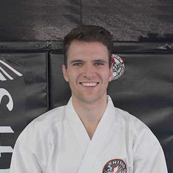 A man in a white karate uniform is smiling for the camera.