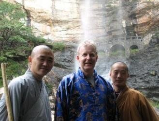 Three men are posing for a picture in front of a waterfall