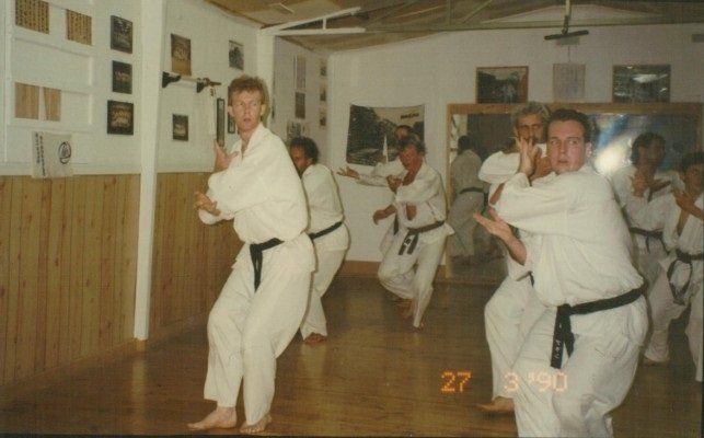 A group of men are practicing martial arts in a room with the date 27 3 1990