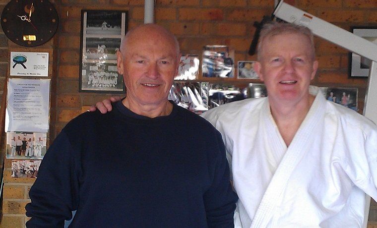 Two men are posing for a picture and one has his arm around the other 's shoulder