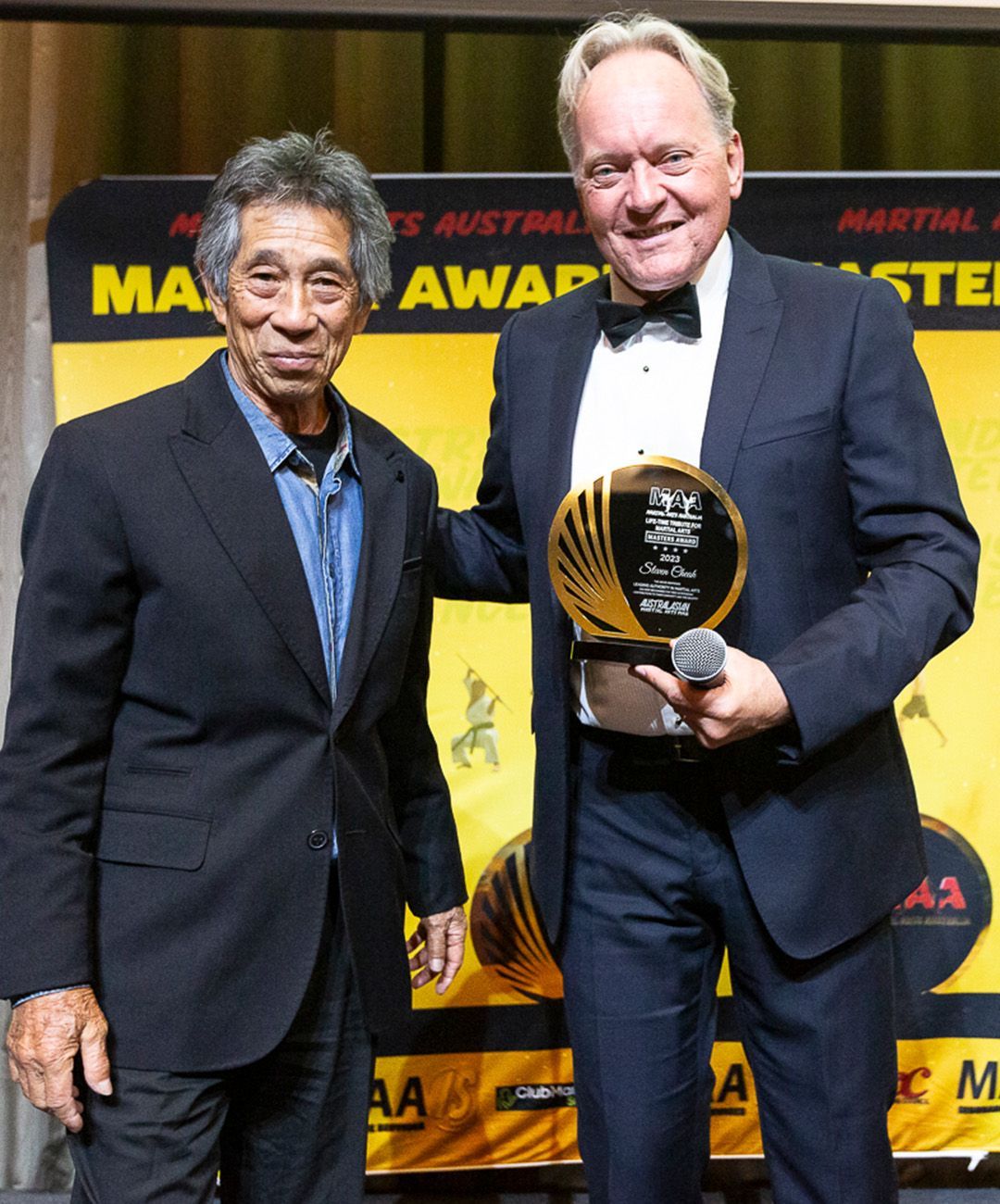 Two men standing in front of a sign that says martial arts awards
