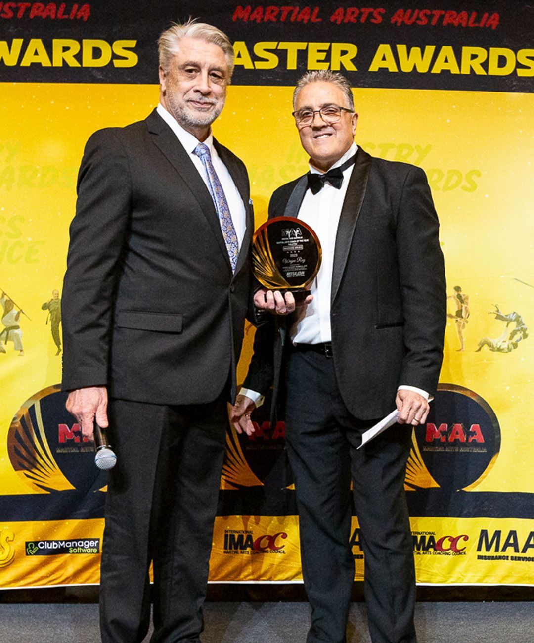 Two men standing in front of a sign that says martial arts australia master awards