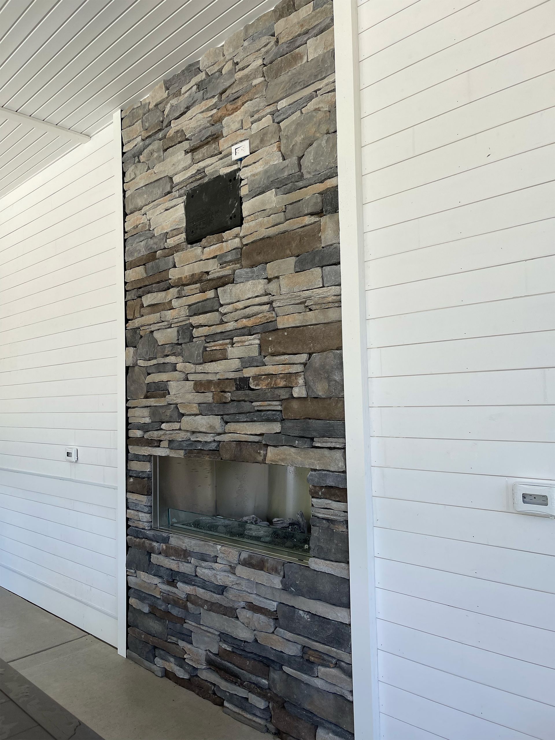 A stone wall with a fireplace in the middle of it.