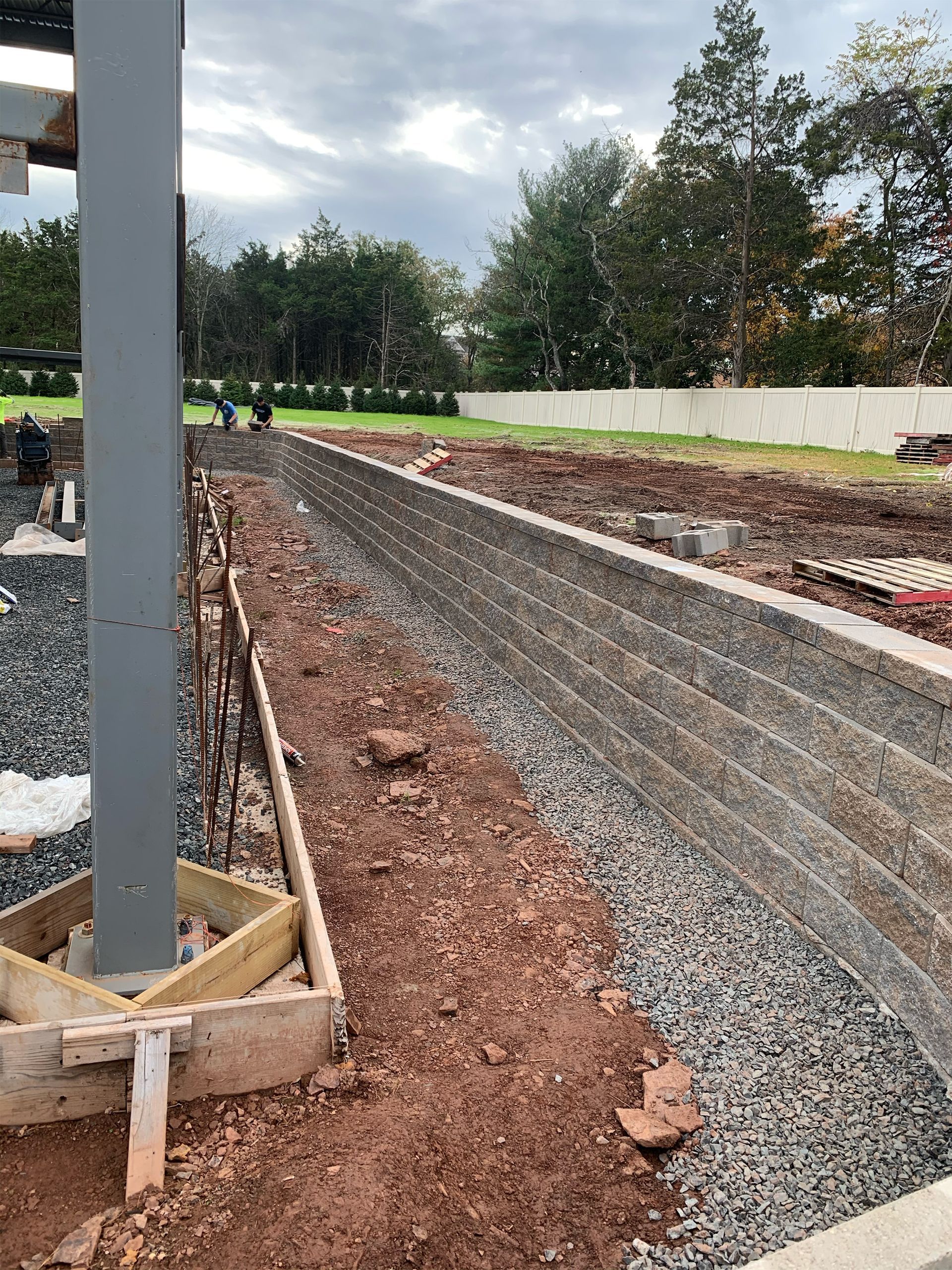 A concrete wall is being built next to a gravel road.