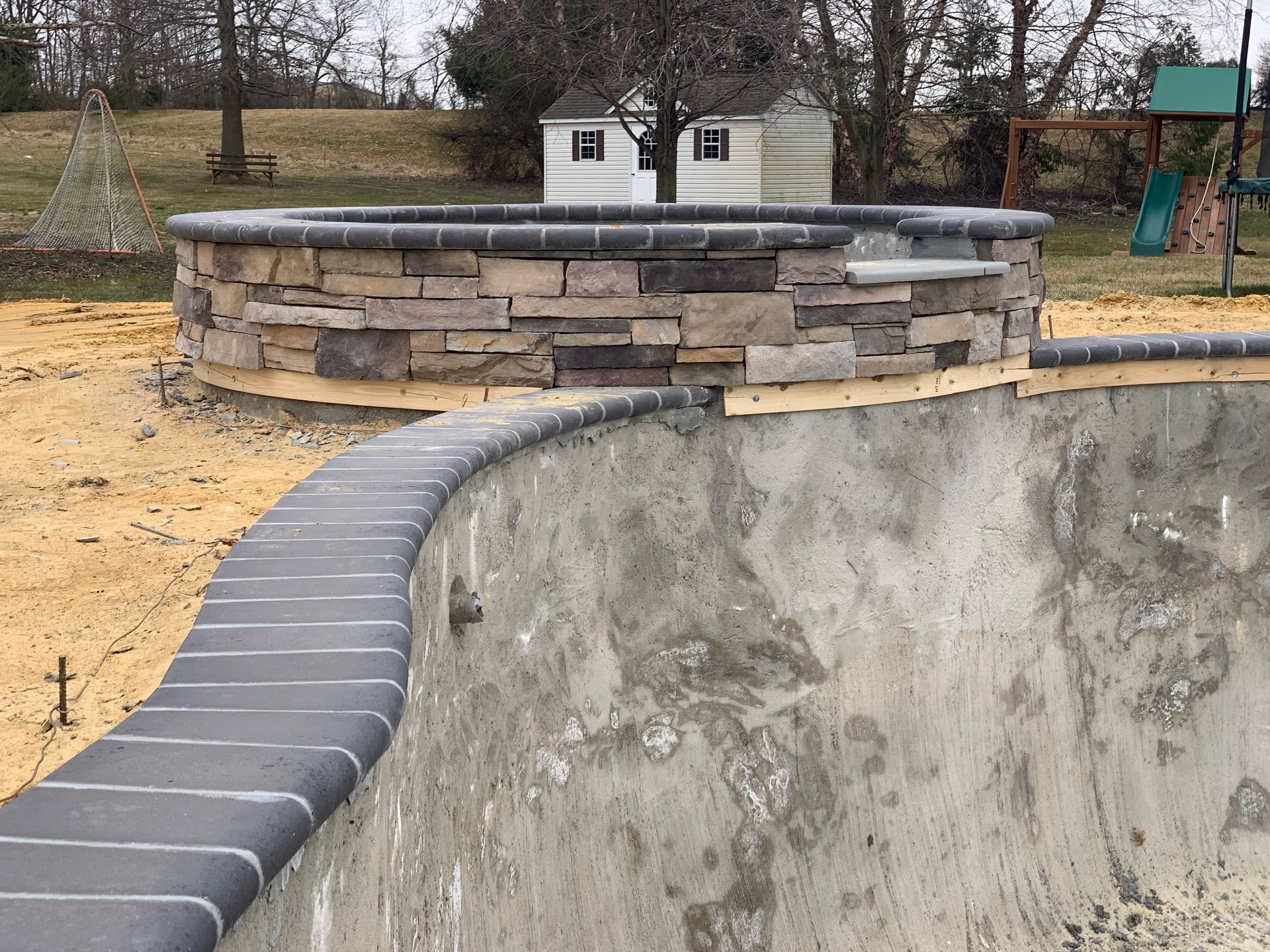 A concrete pool with a stone wall surrounding it.