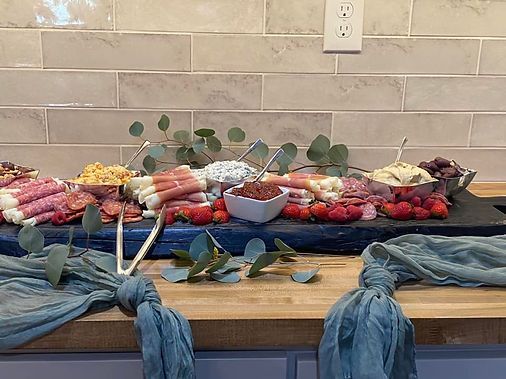 Table with assorted wrapped food, candles, and greenery on a blue cloth for a celebration setup