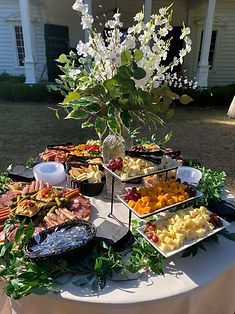 Outdoor buffet table with assorted salads and appetizers on a white tablecloth, decorated with flowers.