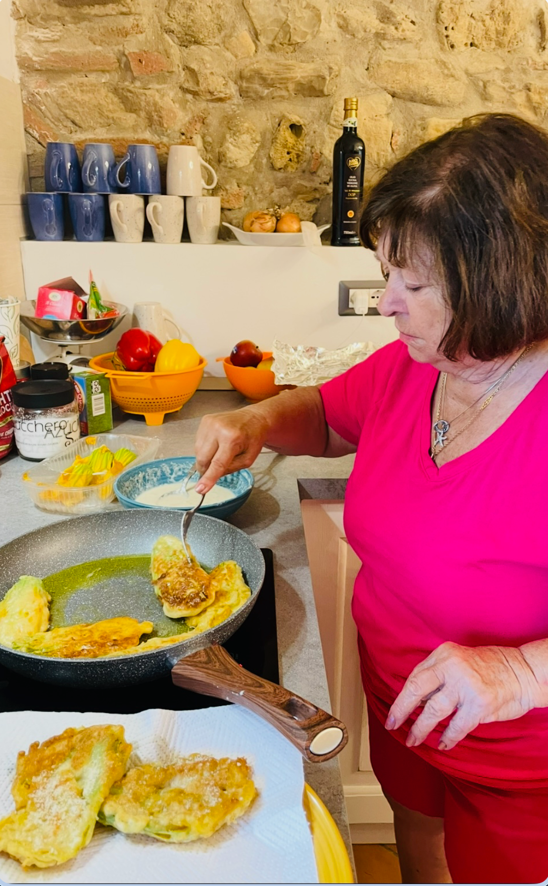 An Italian grandmother teaching a small group to make pasta at a farmhouse table