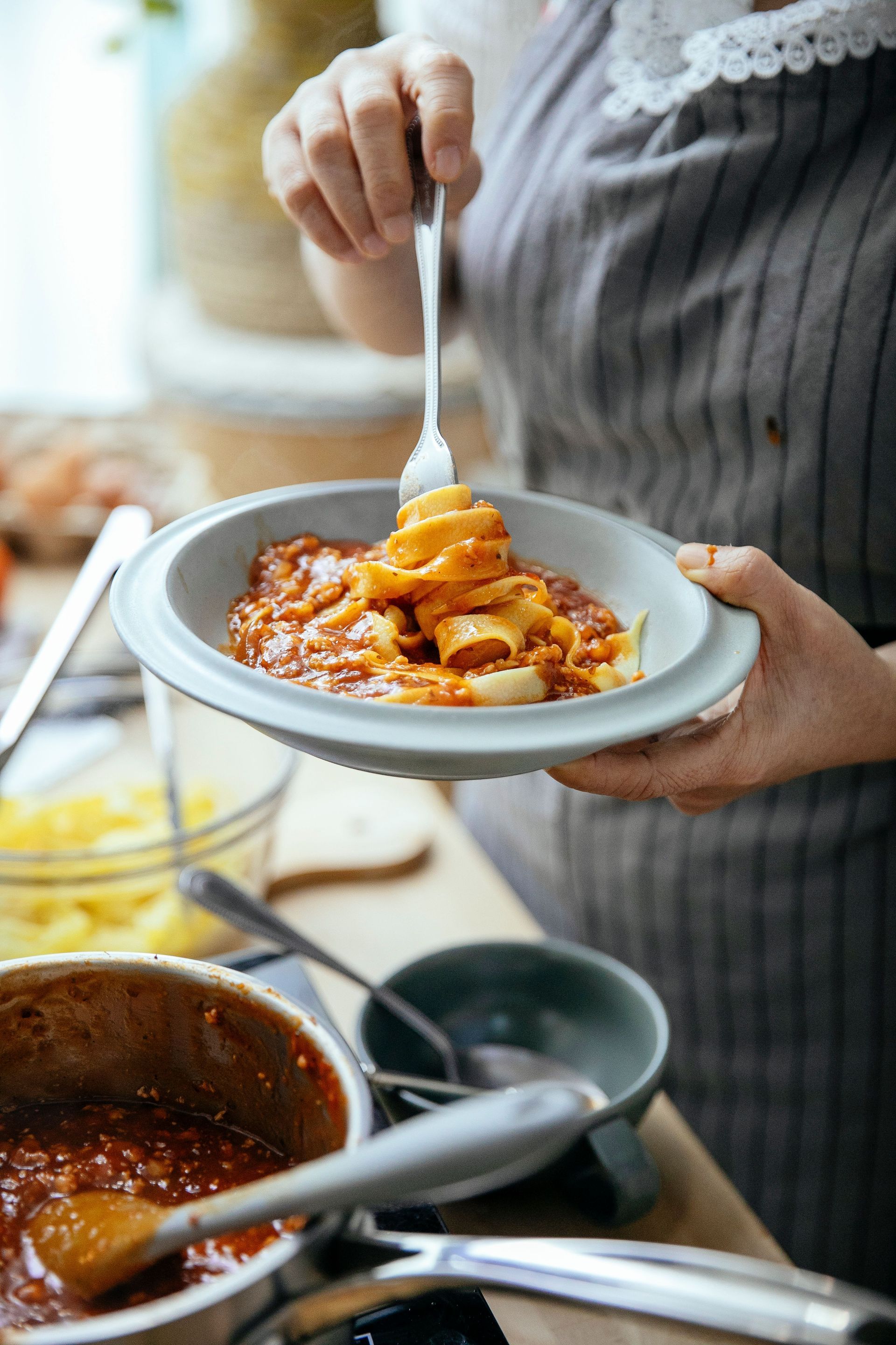 Guests gathered around a rustic kitchen island rolling fresh pasta dough