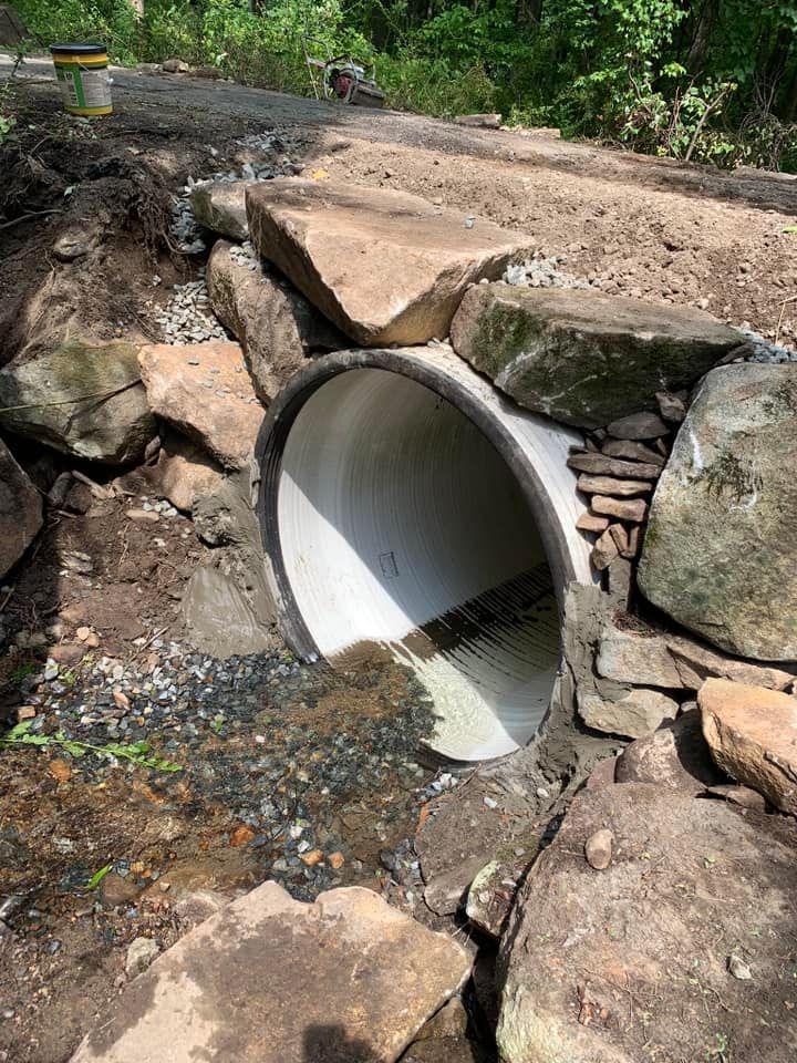 A large pipe is coming out of a rock wall.