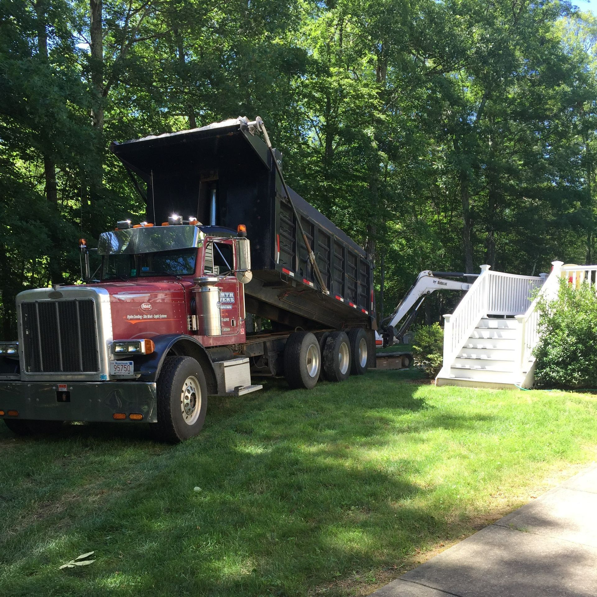 A dump truck is parked in a grassy area with trees in the background