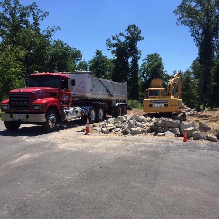A red dump truck is parked next to a yellow excavator
