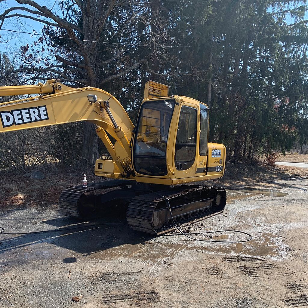 A yellow deere excavator is parked on the side of the road.