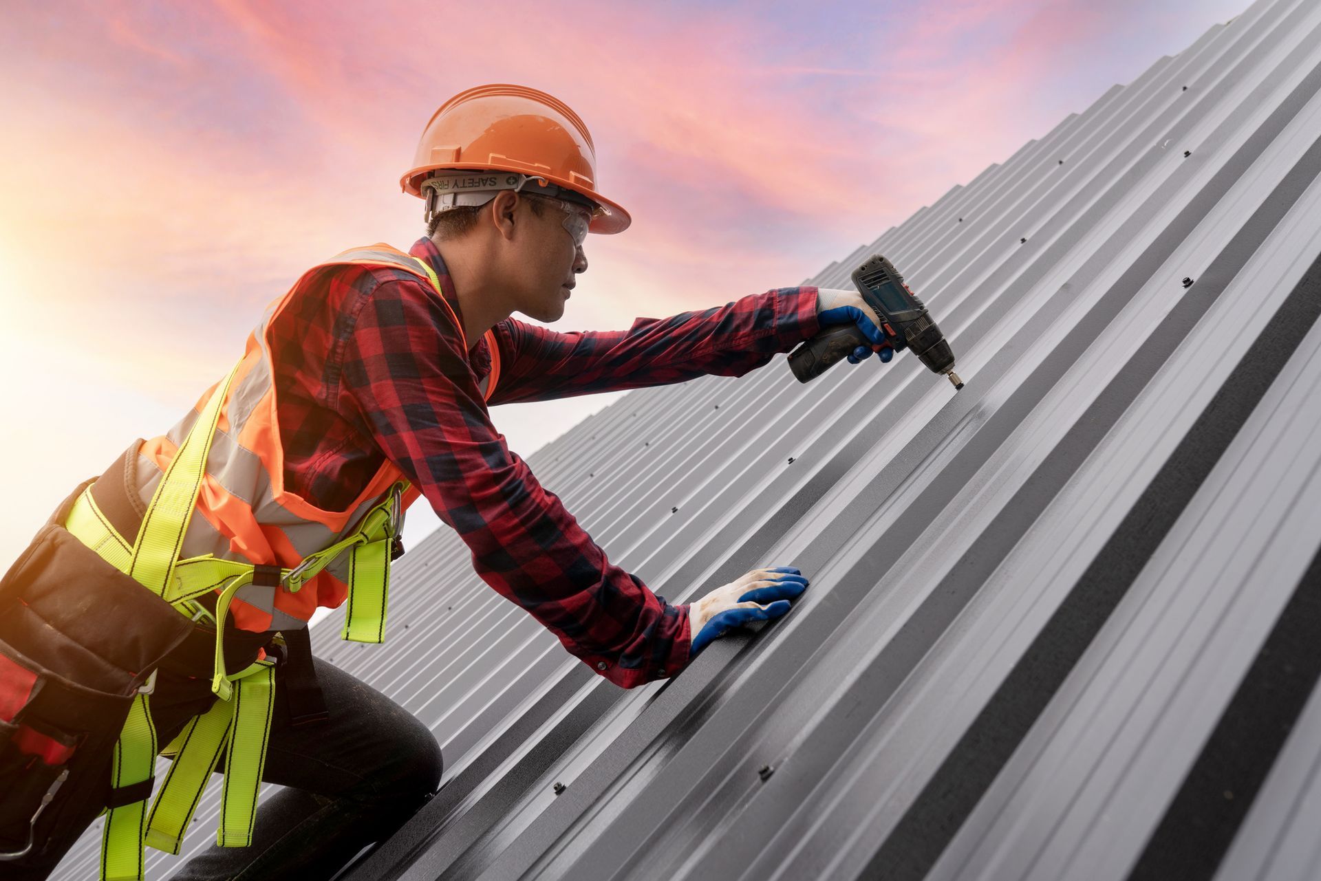 Roofer installing metal sheet roof. Roofer installing metal sheet roof.