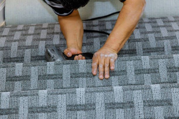 A person is cutting a piece of carpet with a machine.