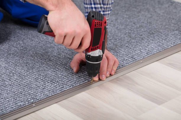 A man is using a drill to install a carpet on the floor.
