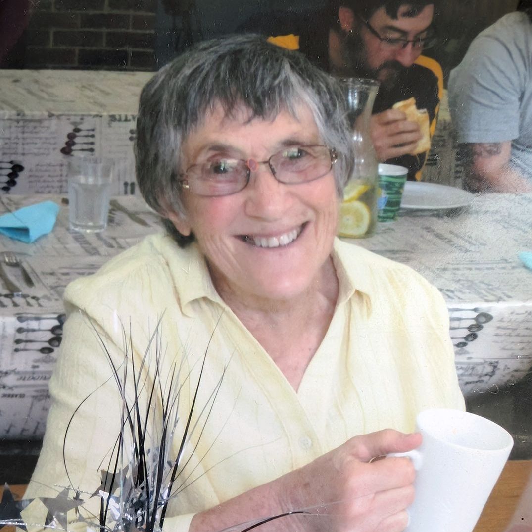 Helen Castles sits at a desk, painting an intricate watercolour piece using a fine paintbrush