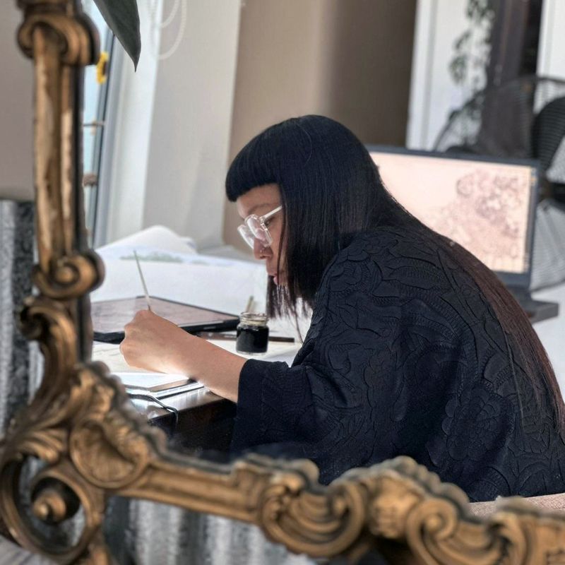 Candice Teok sits at a desk working on an illustration
