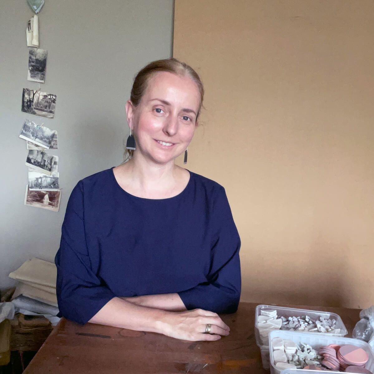 jewellery maker Froni Binns sits at a table, wearing a pair of her own earrings