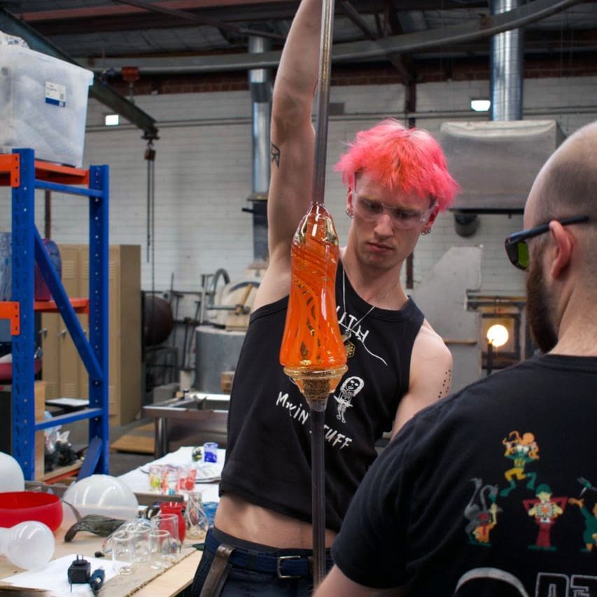 Ty Kouka, a jewellery maker, sits in a cluttered workshop