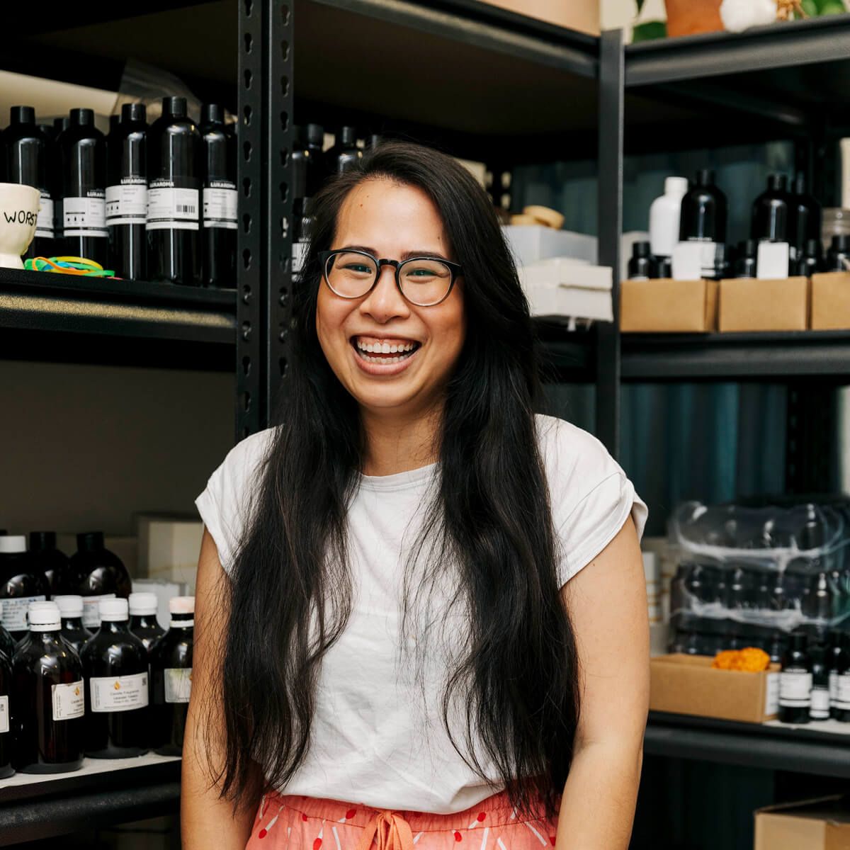 Waan Pivasiri stands in front of shelves full of candle-making materials
