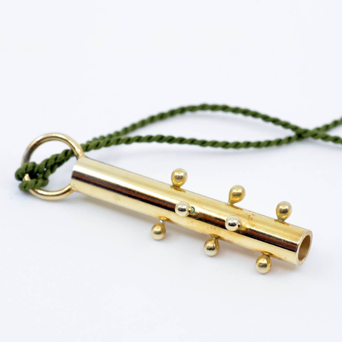 a long, cylindrical gold pendant hanging from dark green twine