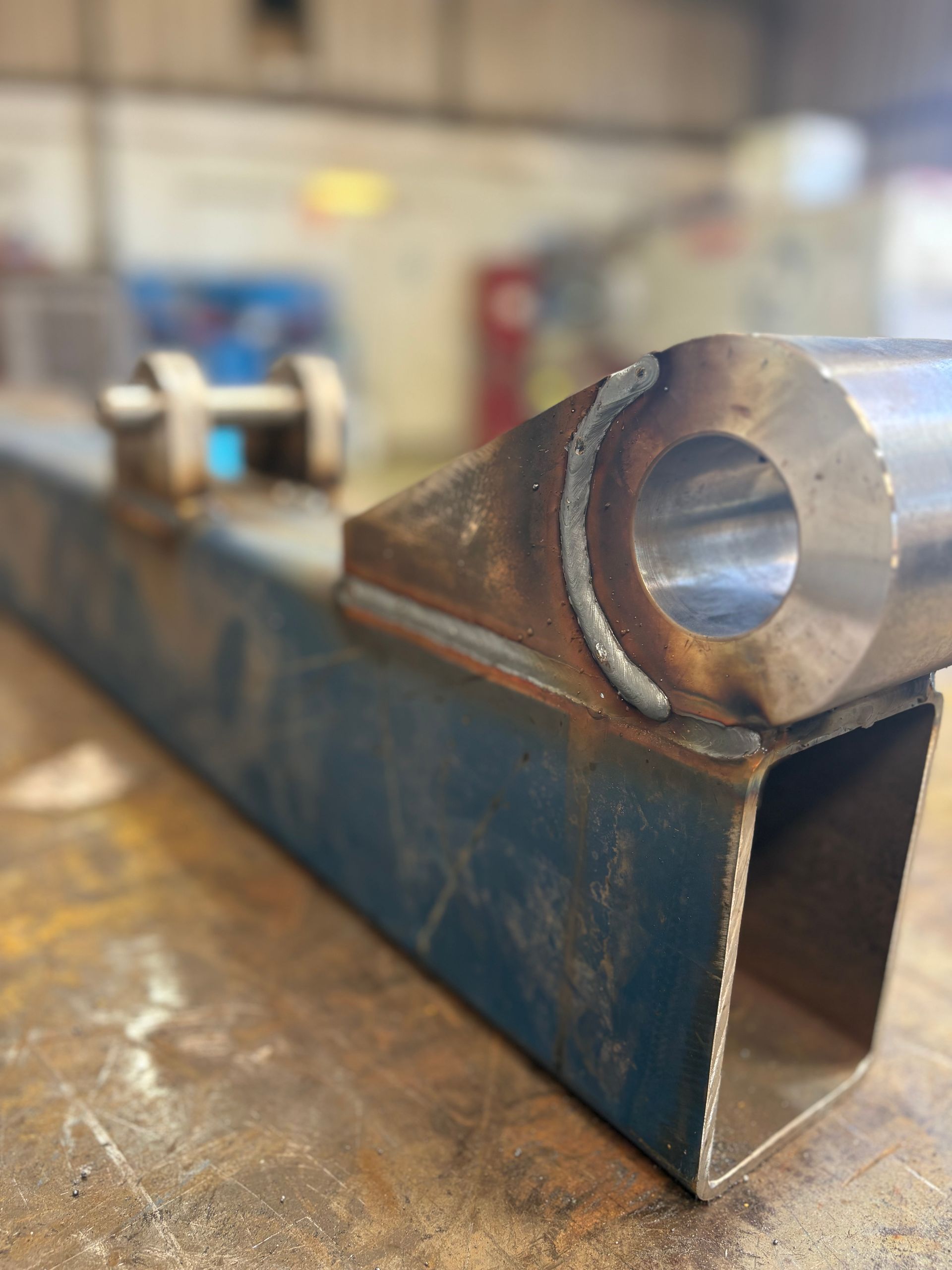 Welded metal frame with a tube and bracket, on a workbench.