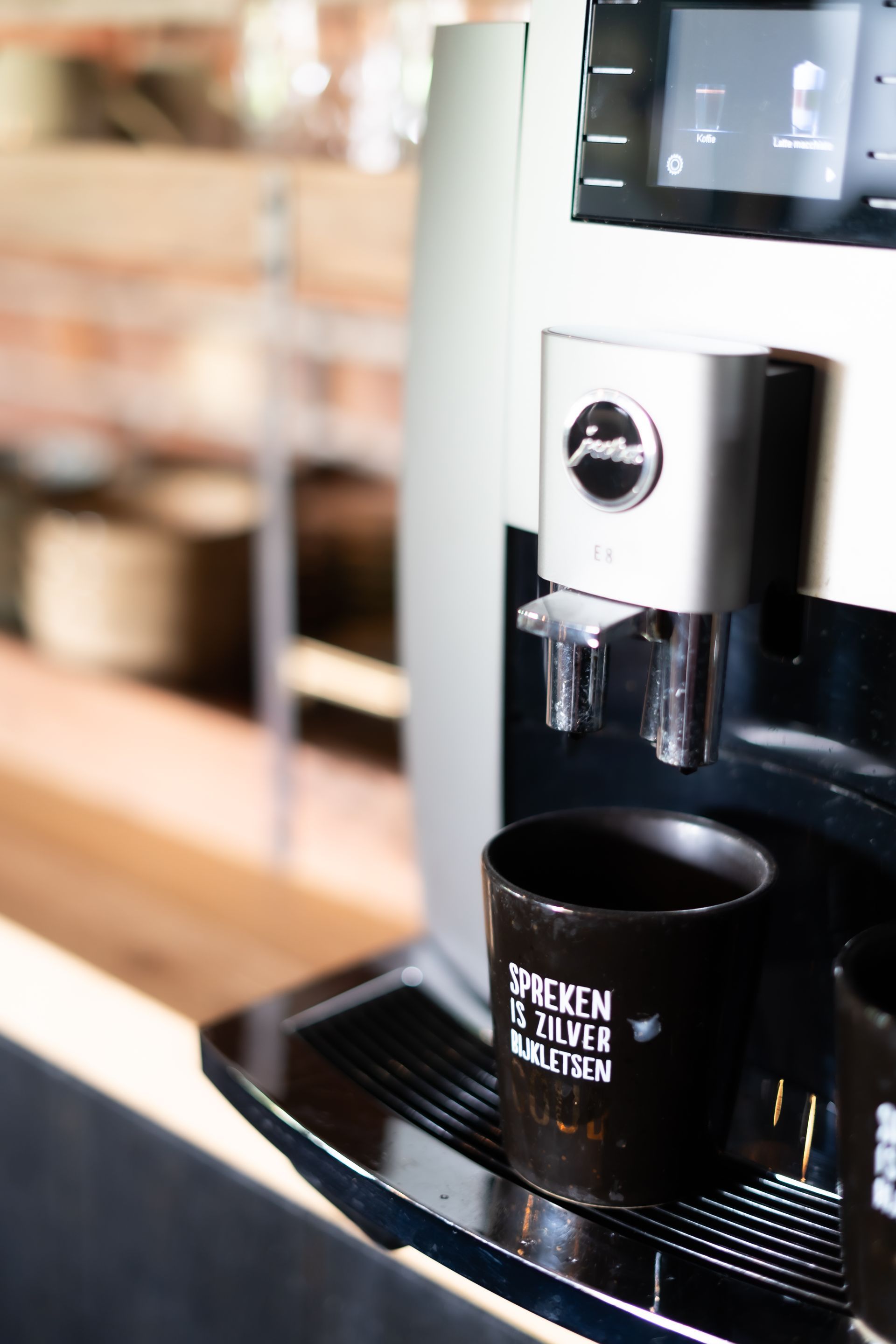 Close-up van een koffiemachine die koffie schenkt in een zwarte mok op het lekbakje.